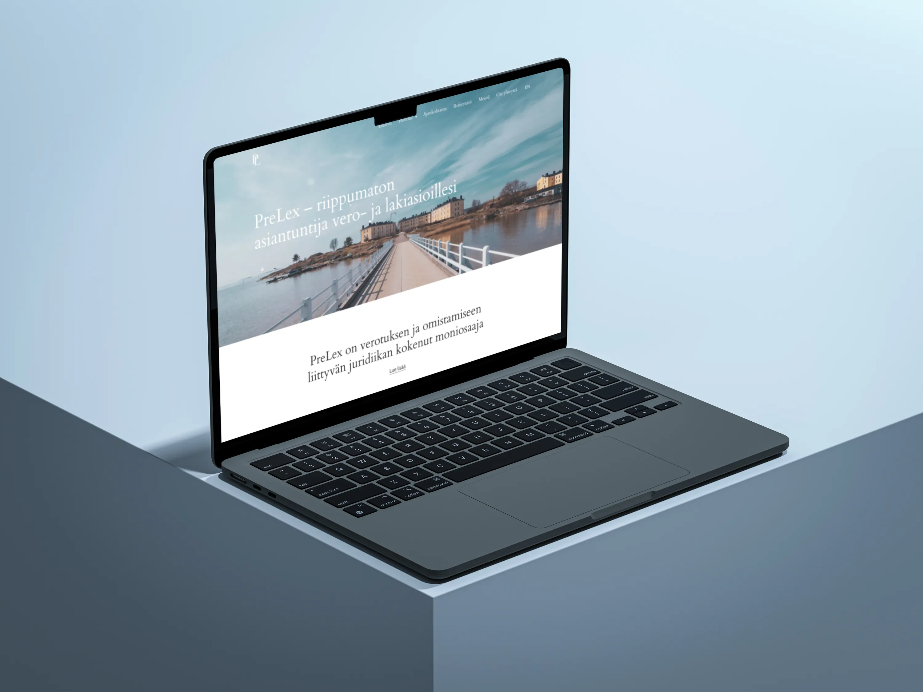 A gray laptop displays a website with Finnish text on a light blue background with soft lighting.